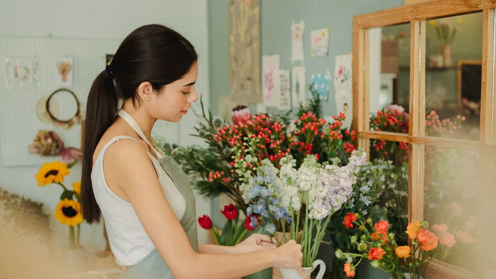 Fleuriste préparant un bouquet coloré au comptoir de sa boutique en pleine lumière