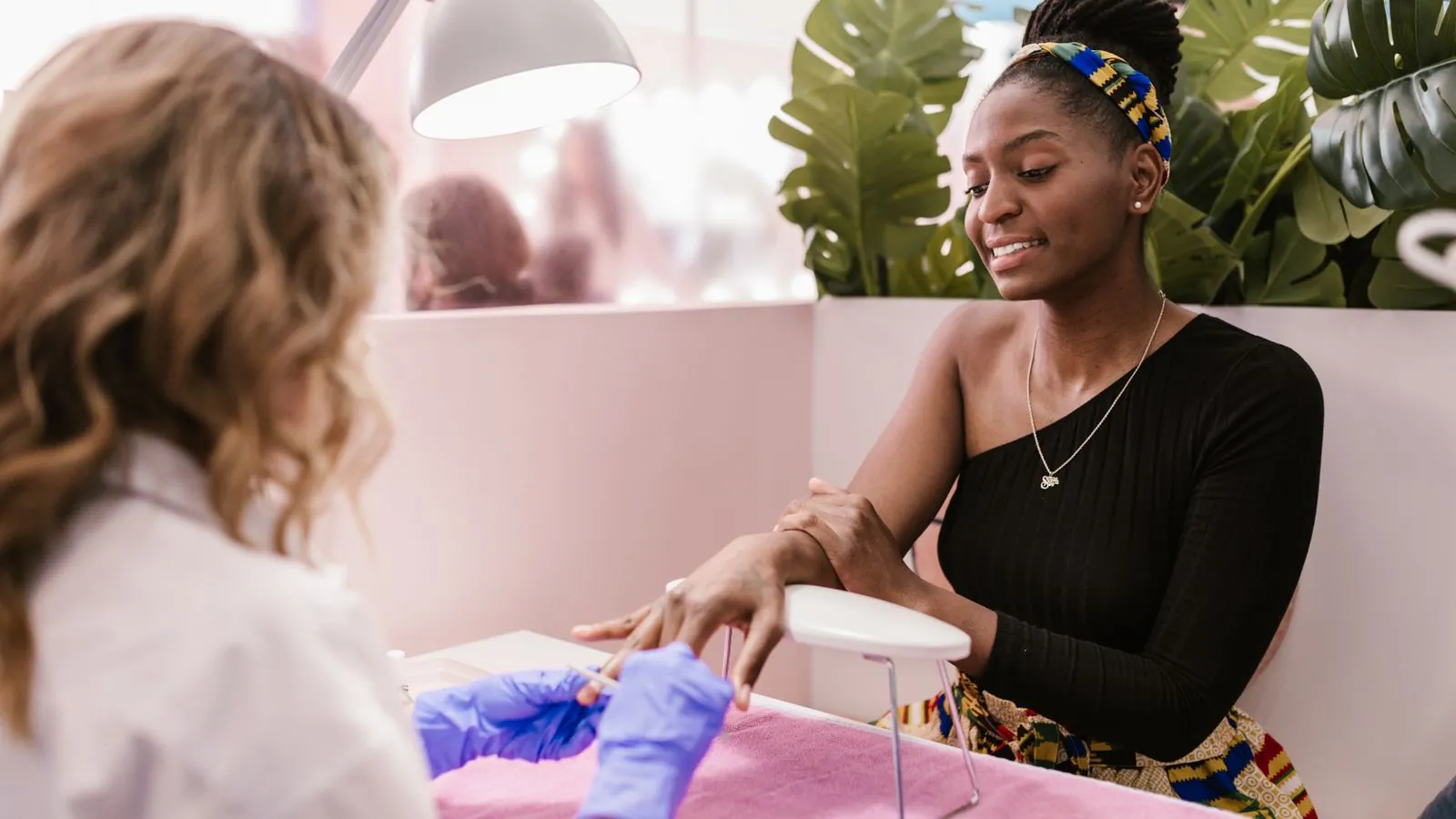 Prothésiste ongulaire posant un vernis sur les ongles d'une cliente en institut lumineux