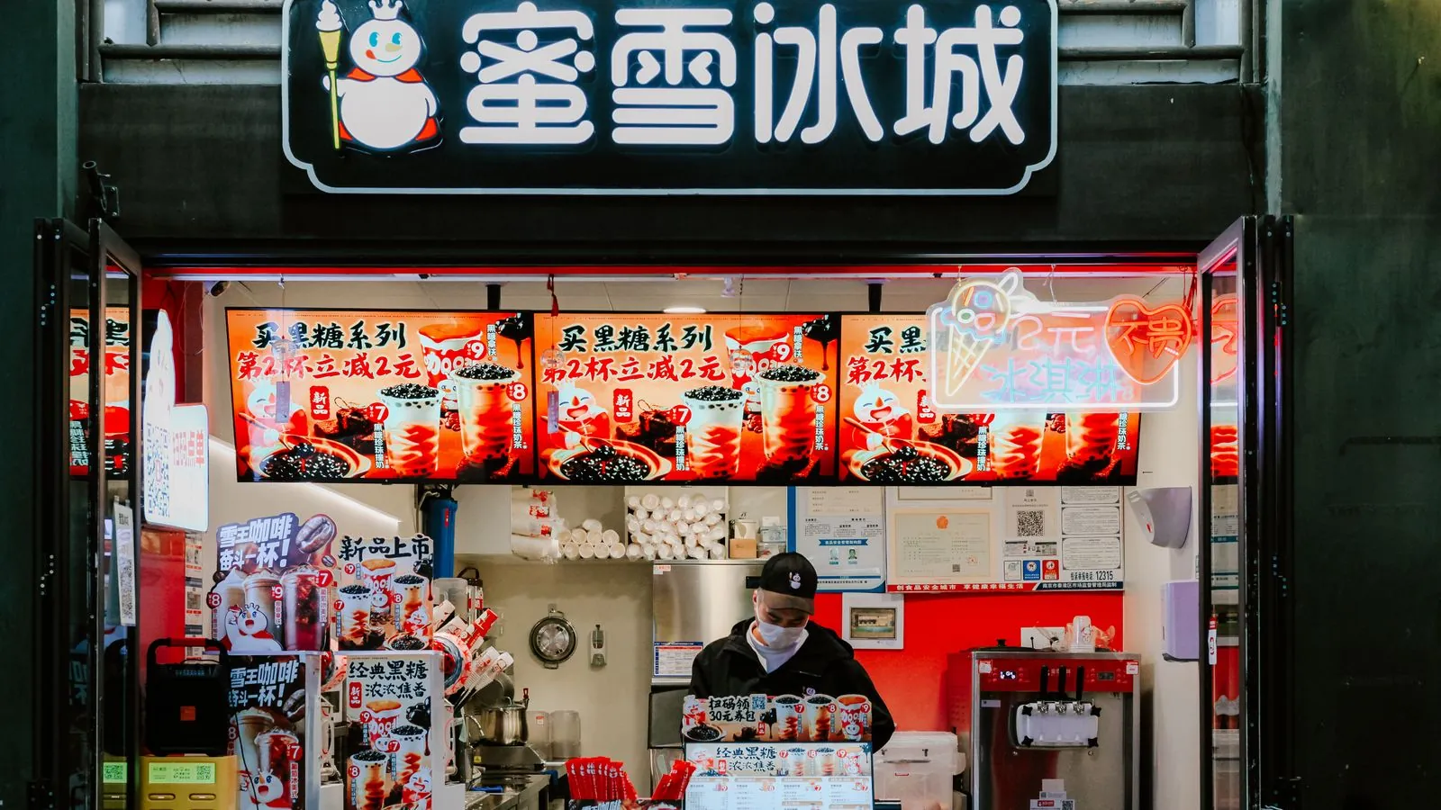 Gobelets de bubble tea colorés avec perles tapioca visibles tenus devant un comptoir