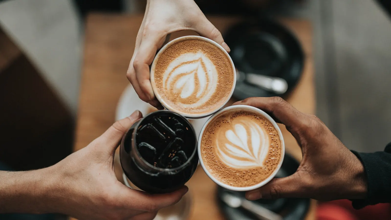 Trois personnes tenant des tasses de café dans un coffee shop
