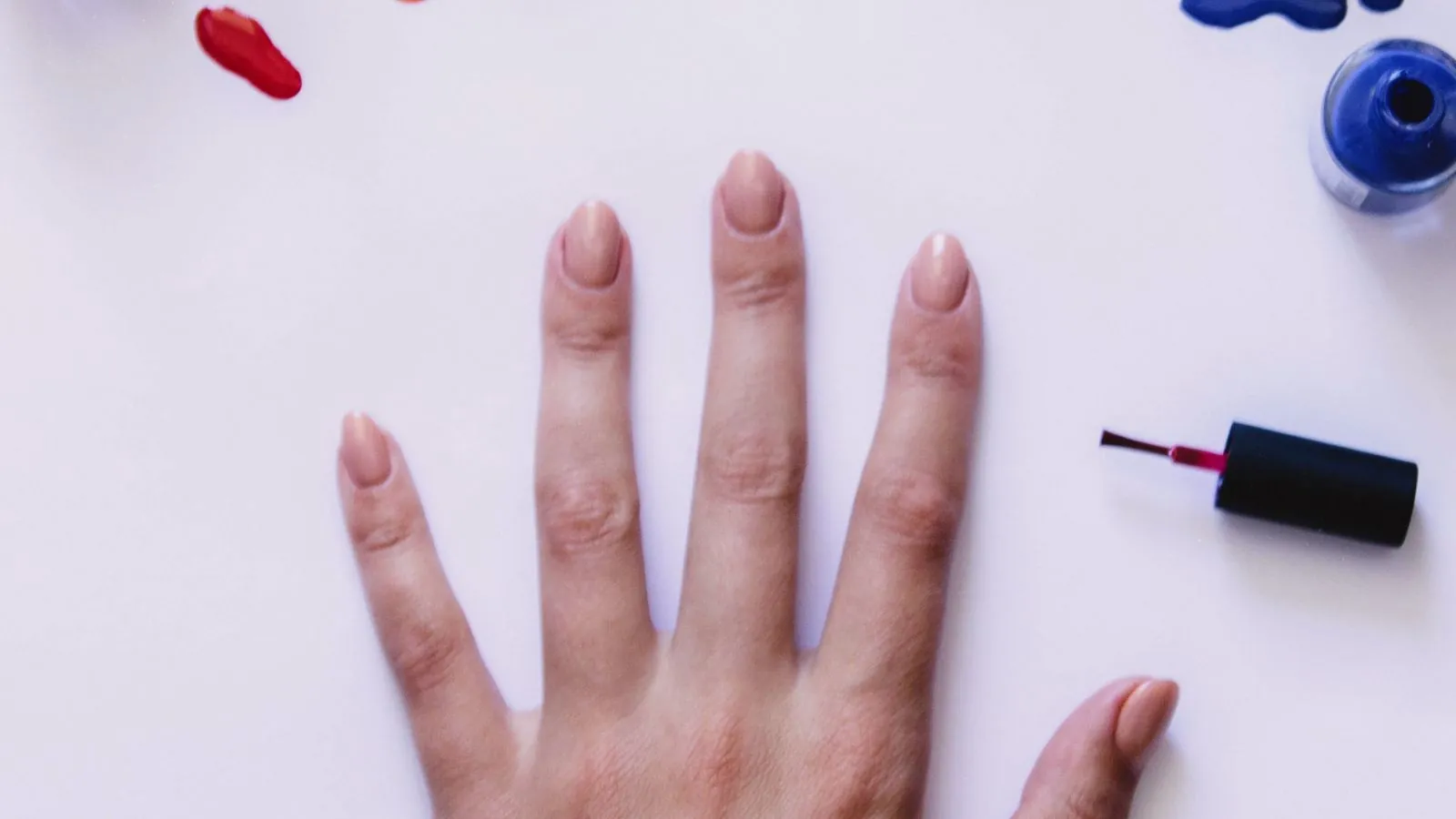 Prothésiste ongulaire installée chez une cliente avec sa lampe UV et ses vernis sur une petite table