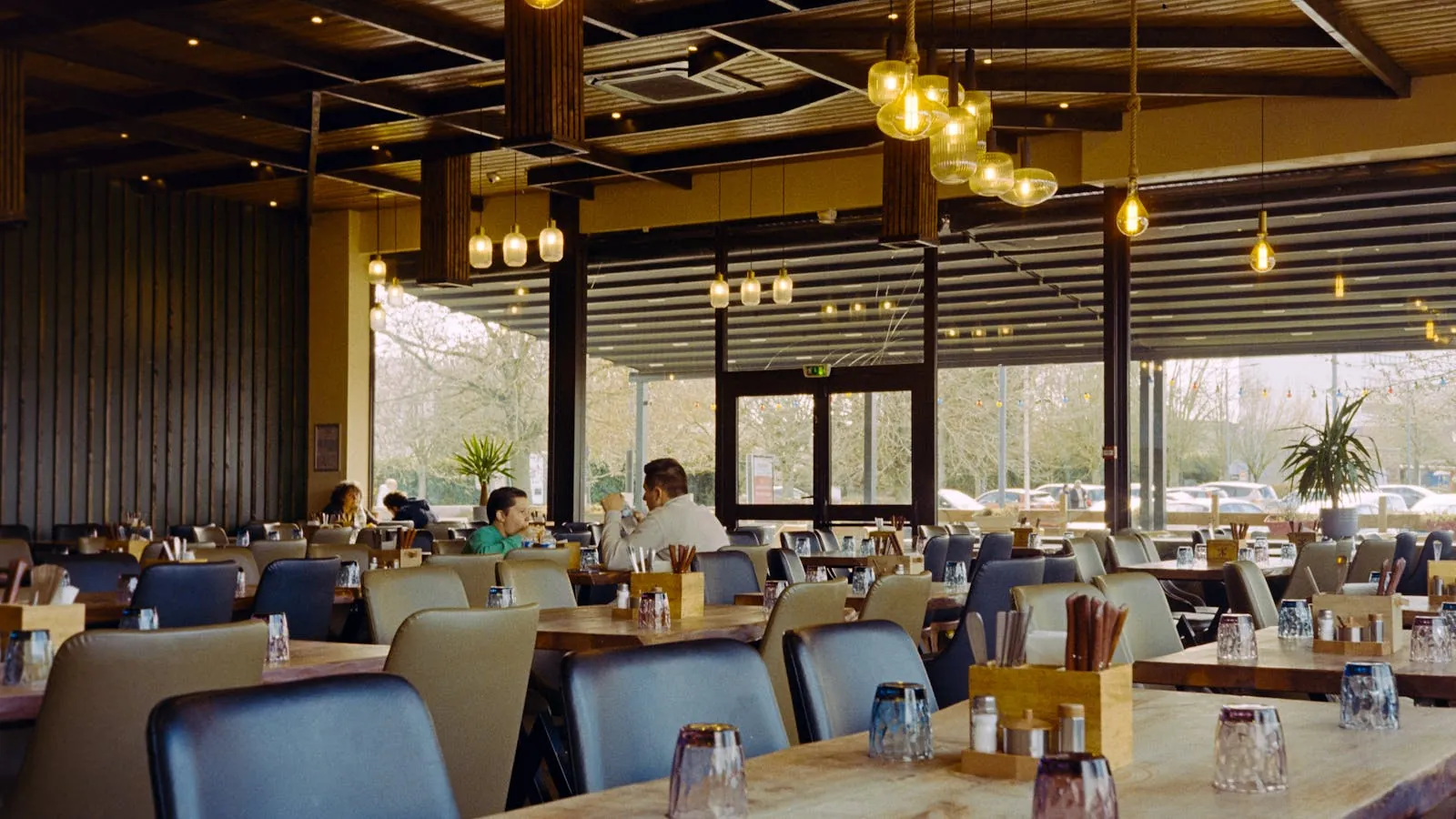 Terrasse de brasserie parisienne en fin d'après-midi, tables et chaises en rotin sous l'auvent