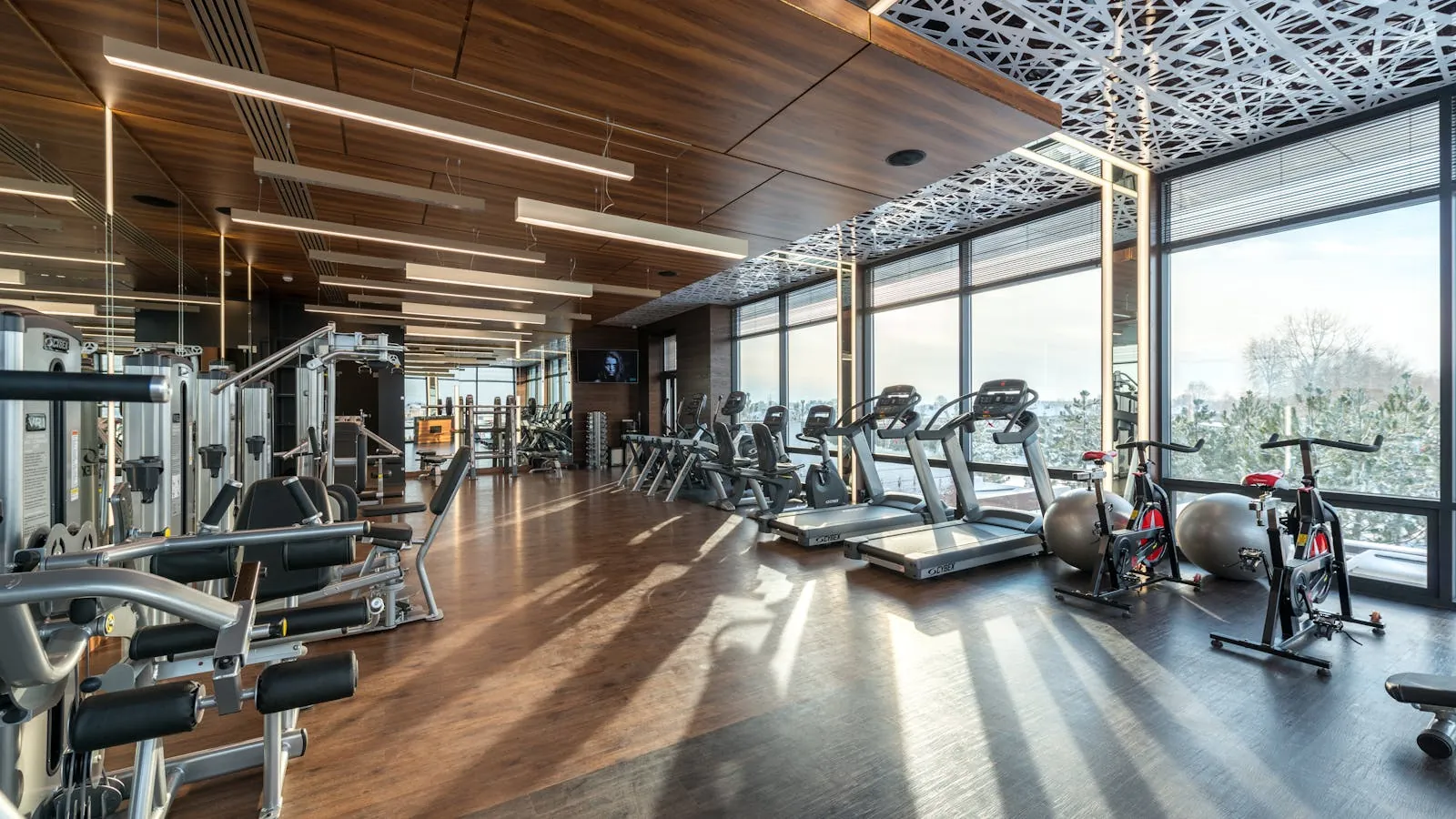 Adhérent s'entraînant à la salle de sport au lever du jour, lumière par les baies vitrées
