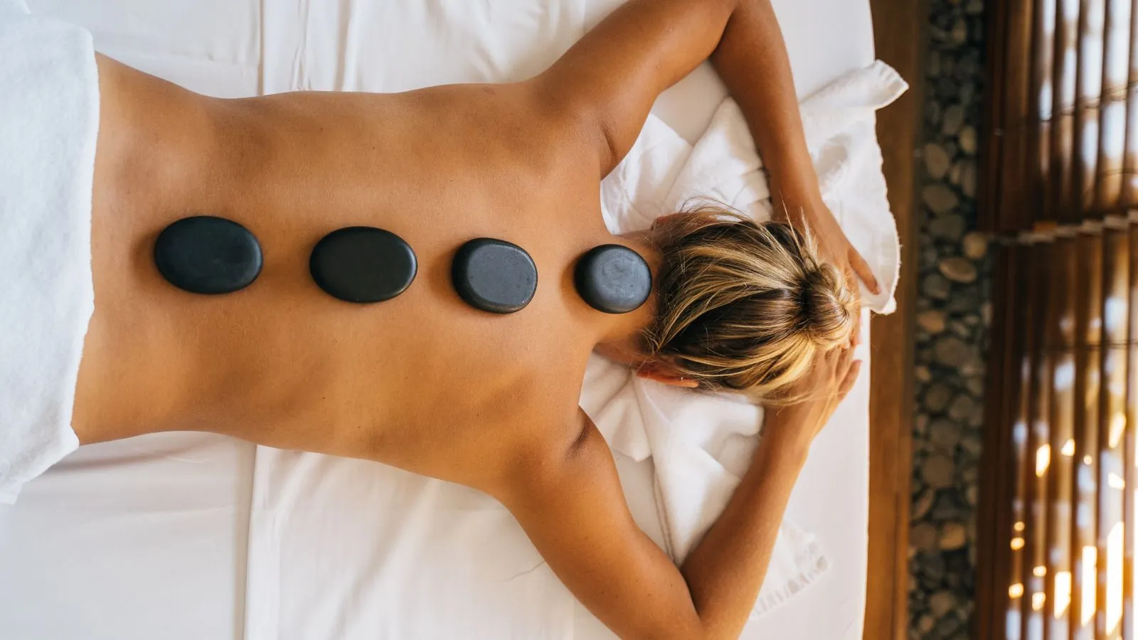 Cabine de spa avec table de massage, bougies et serviettes pliées dans une lumière tamisée