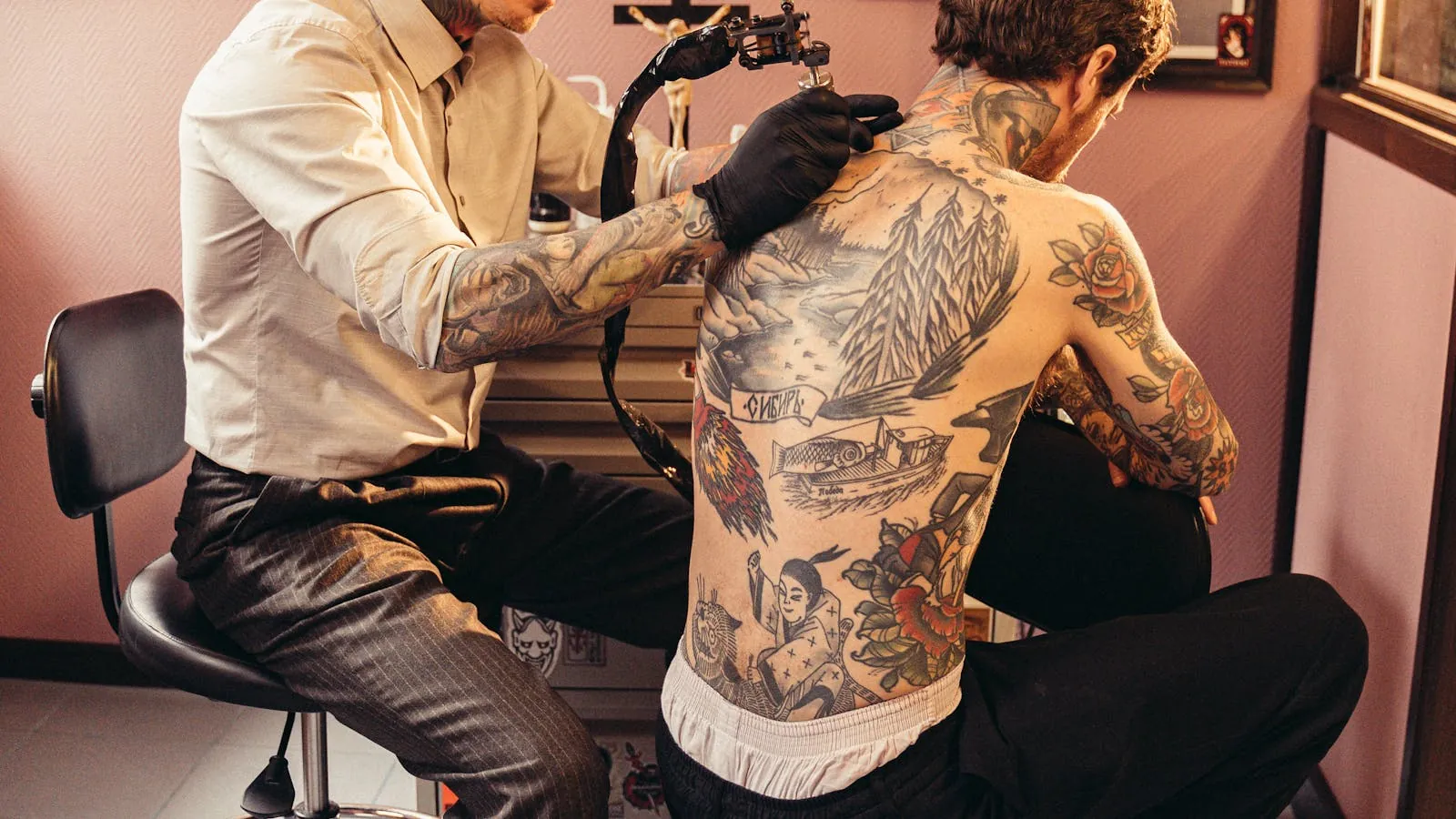 Tatoueur concentré tatouant l'avant-bras d'un client dans un studio au style brut